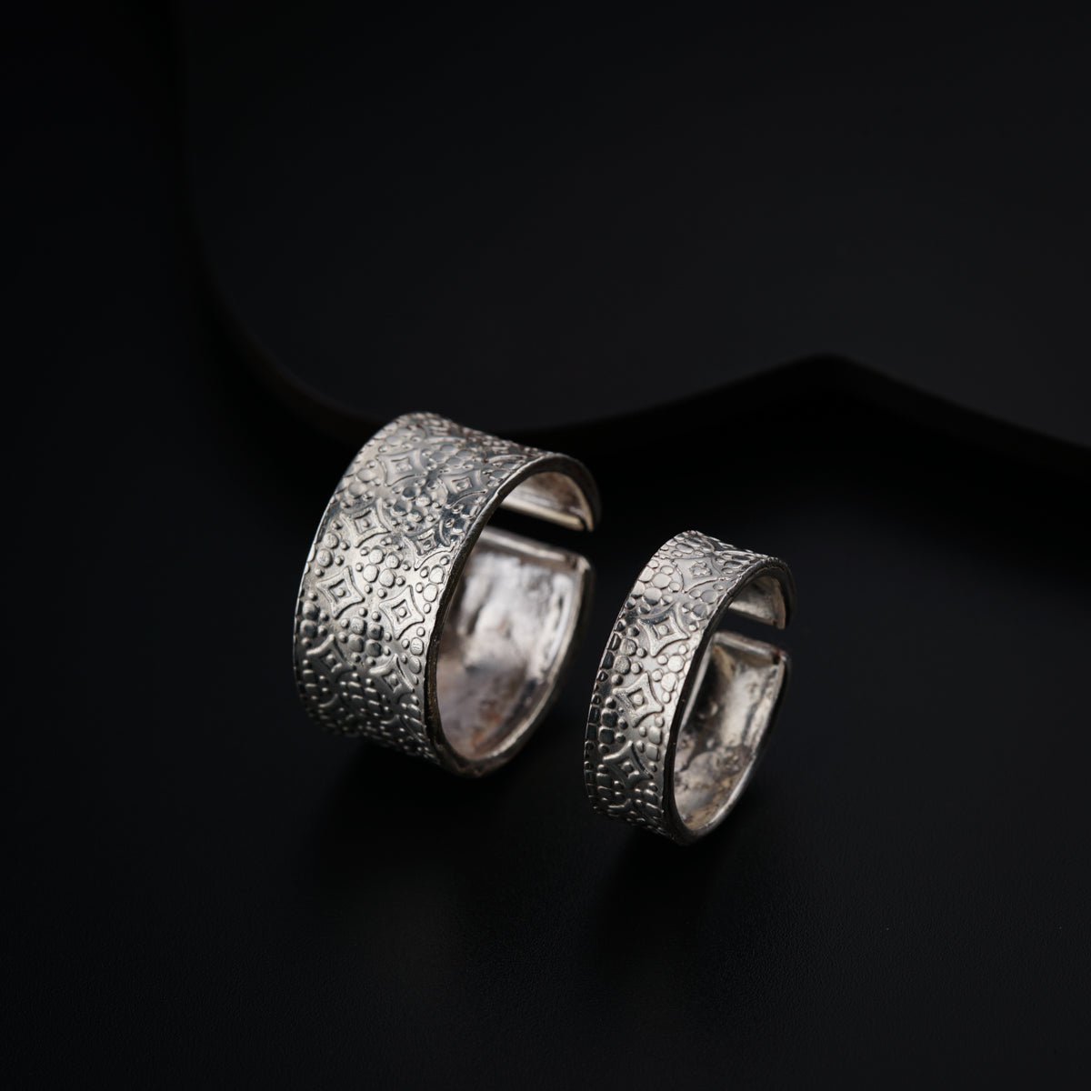 a pair of silver rings sitting on top of a black surface
