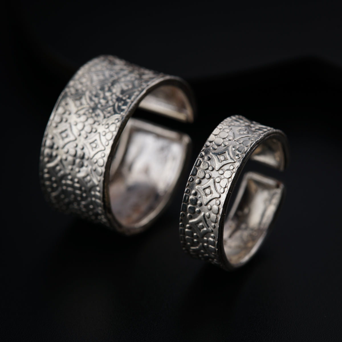 two silver rings sitting on top of a black surface