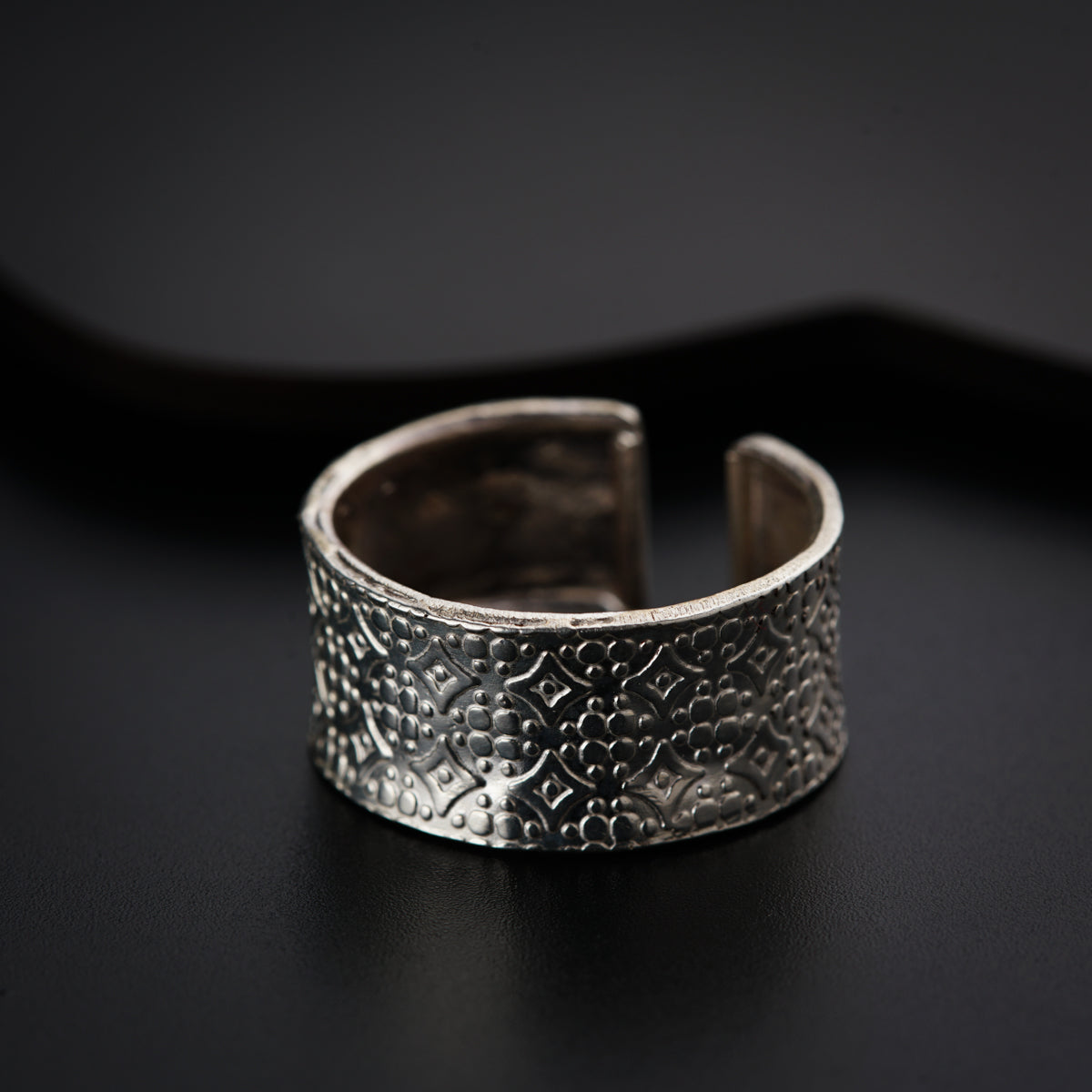 a close up of a silver ring on a black surface