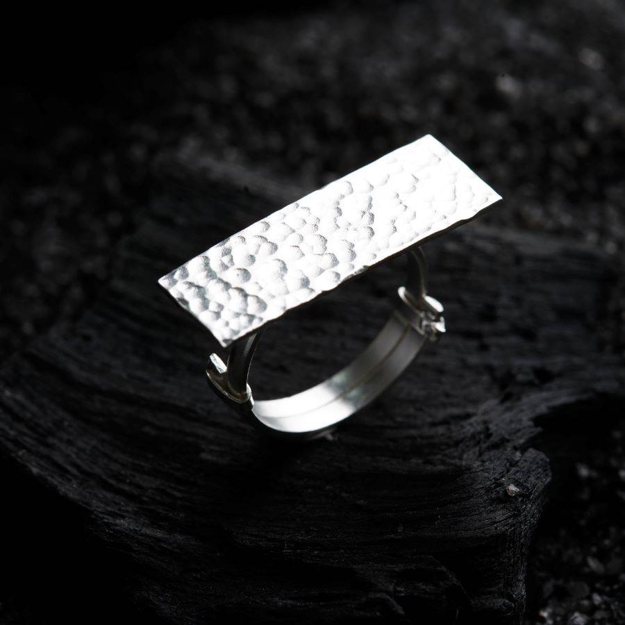 a silver ring sitting on top of a piece of wood