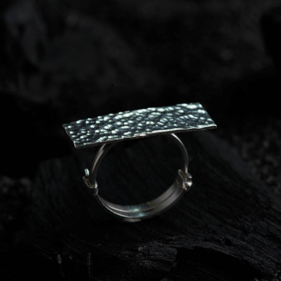 a close up of a silver ring on a black surface