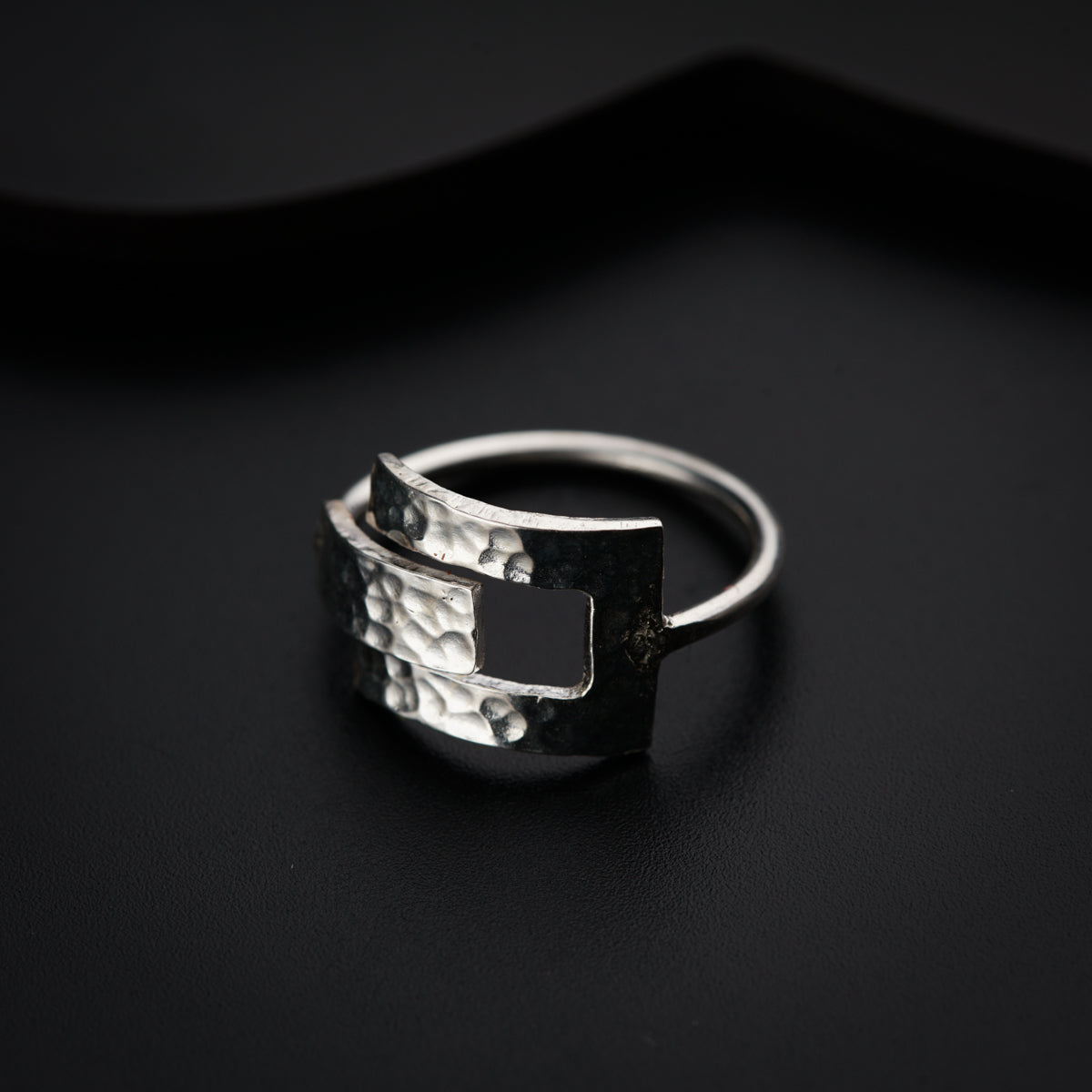 a silver ring sitting on top of a black surface