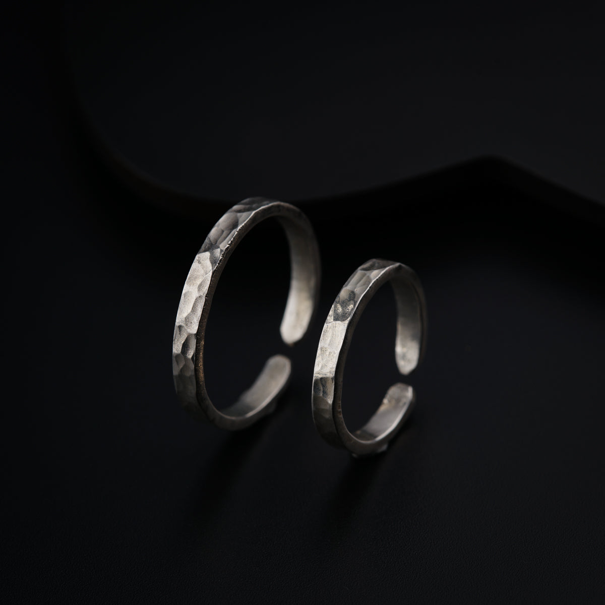 a pair of silver rings sitting on top of a black surface