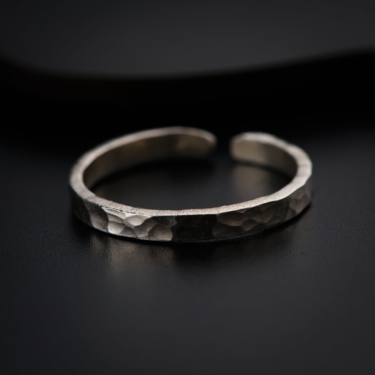 a close up of a silver ring on a black surface