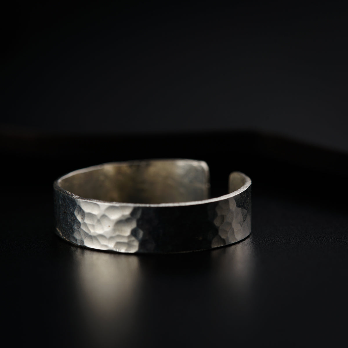 a close up of a silver ring on a black surface