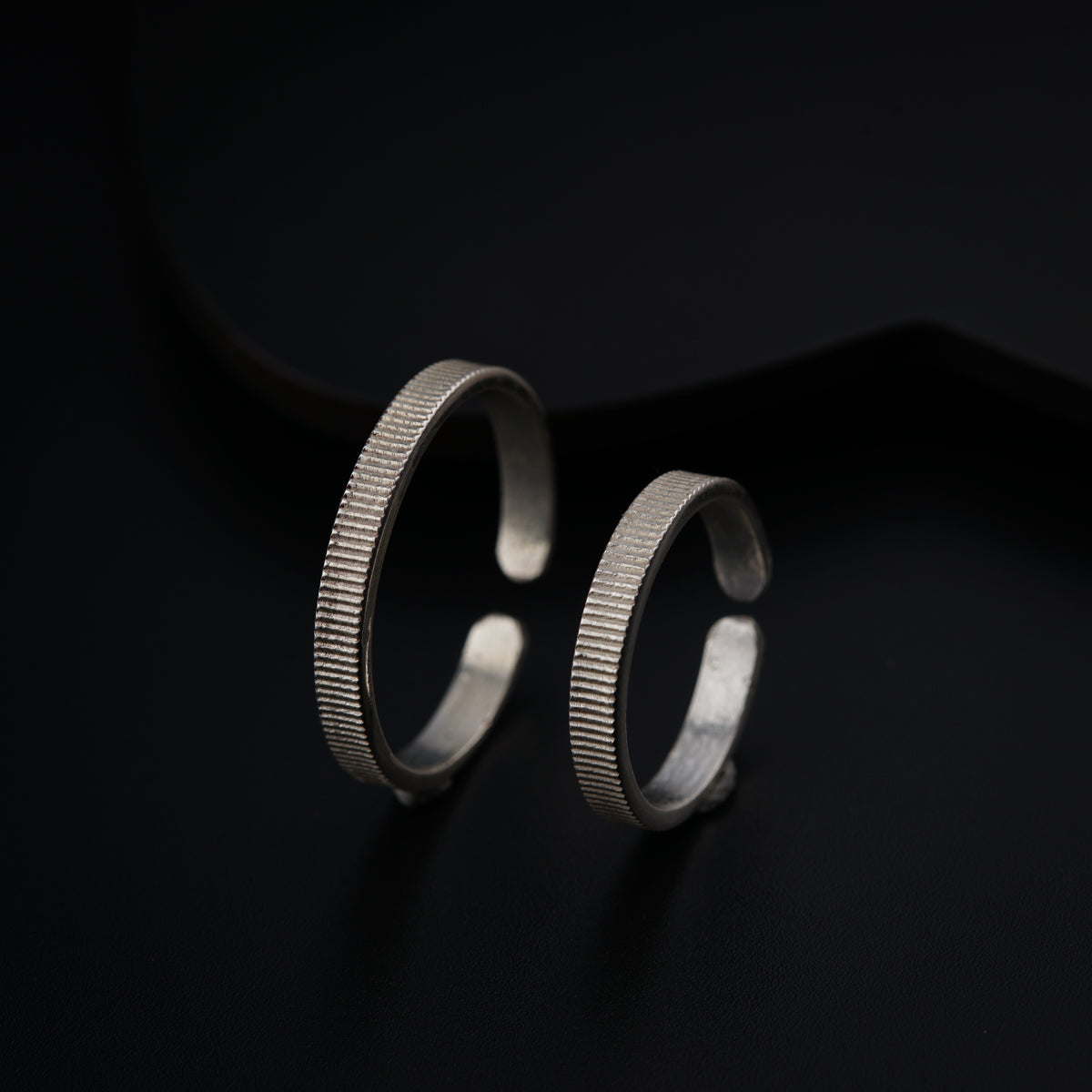 a pair of silver rings sitting on top of a black surface