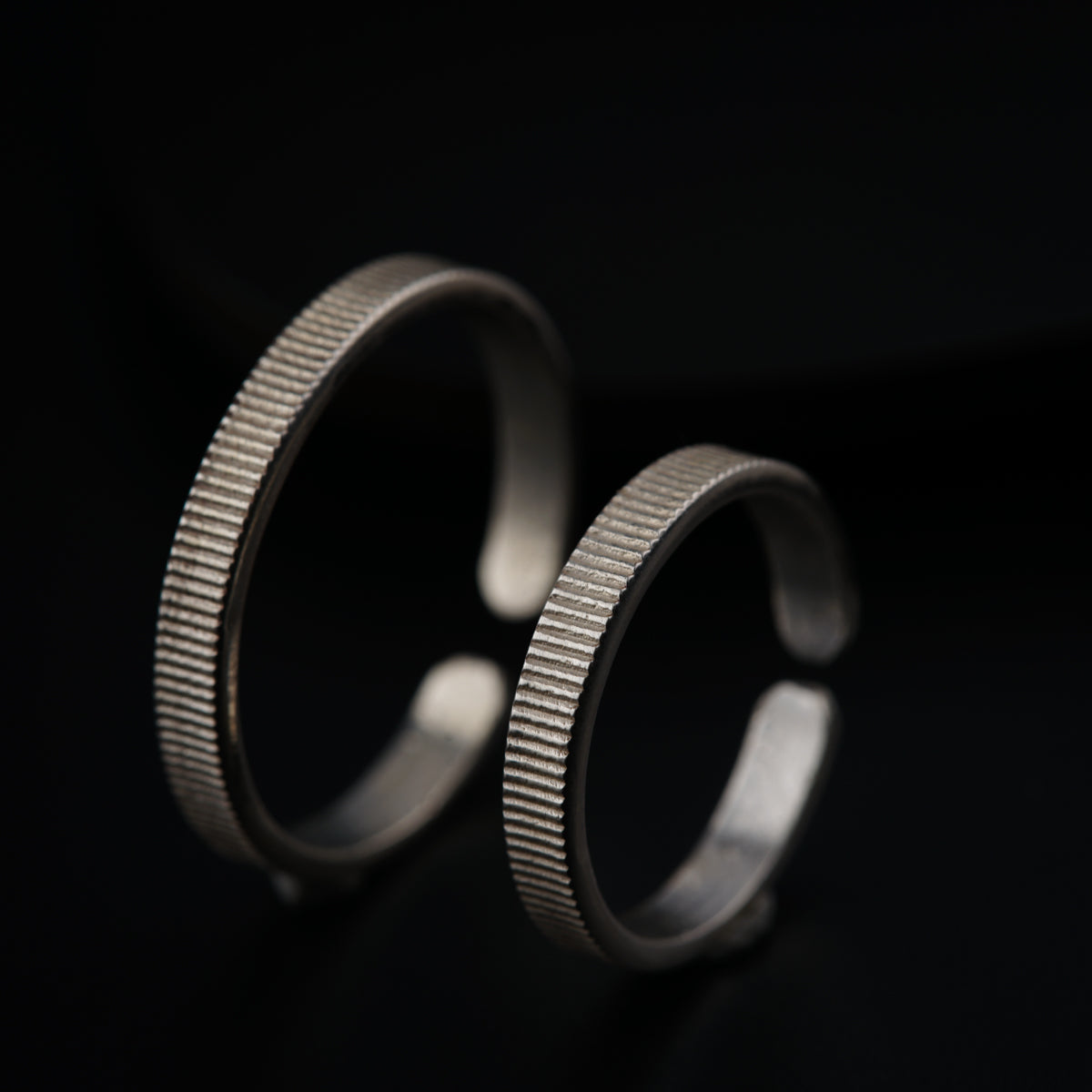 two silver rings sitting next to each other on a black surface