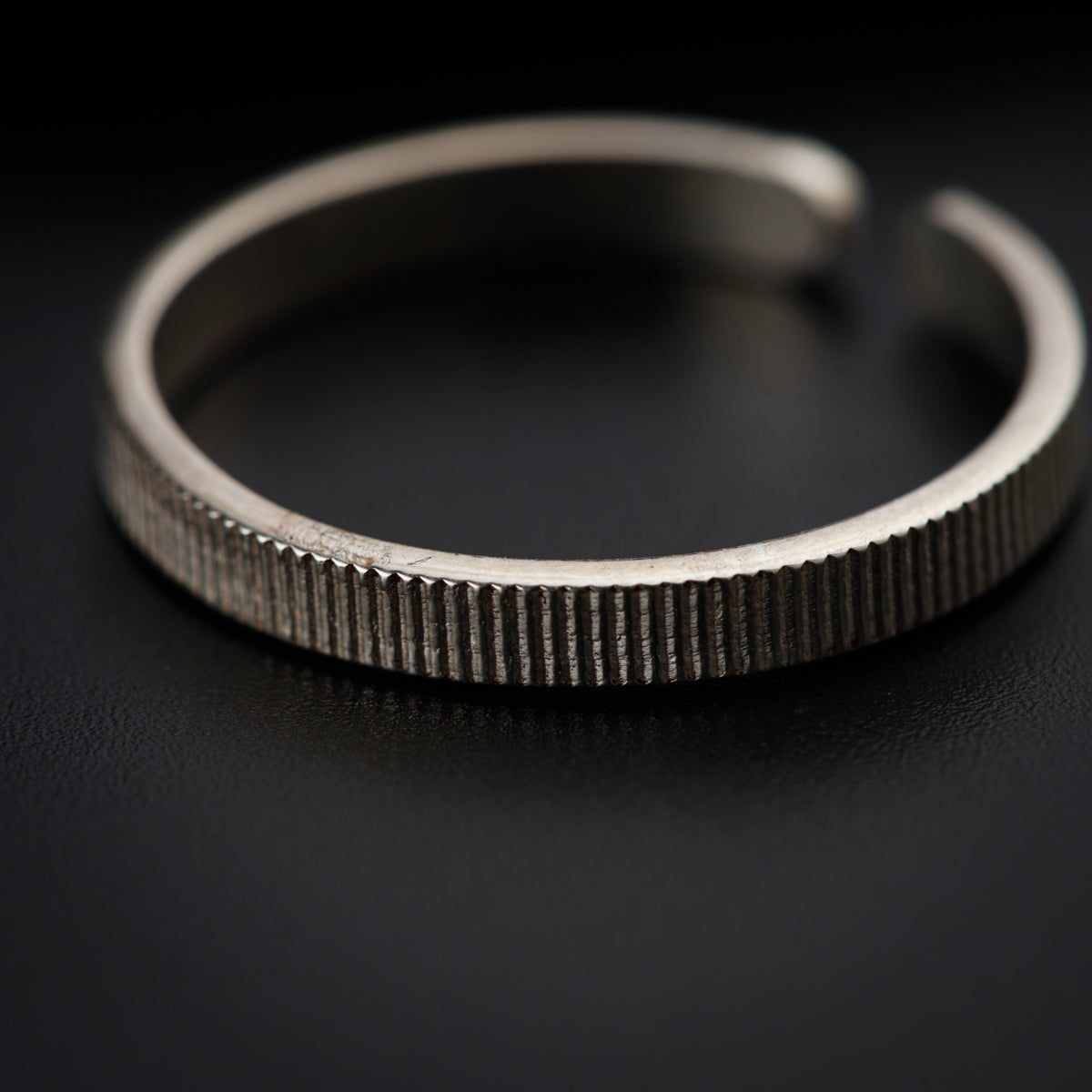 a close up of a silver bracelet on a black surface