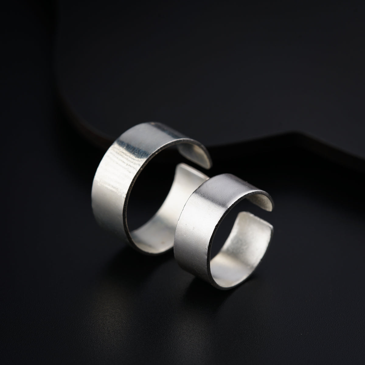 two silver rings sitting on top of a black surface