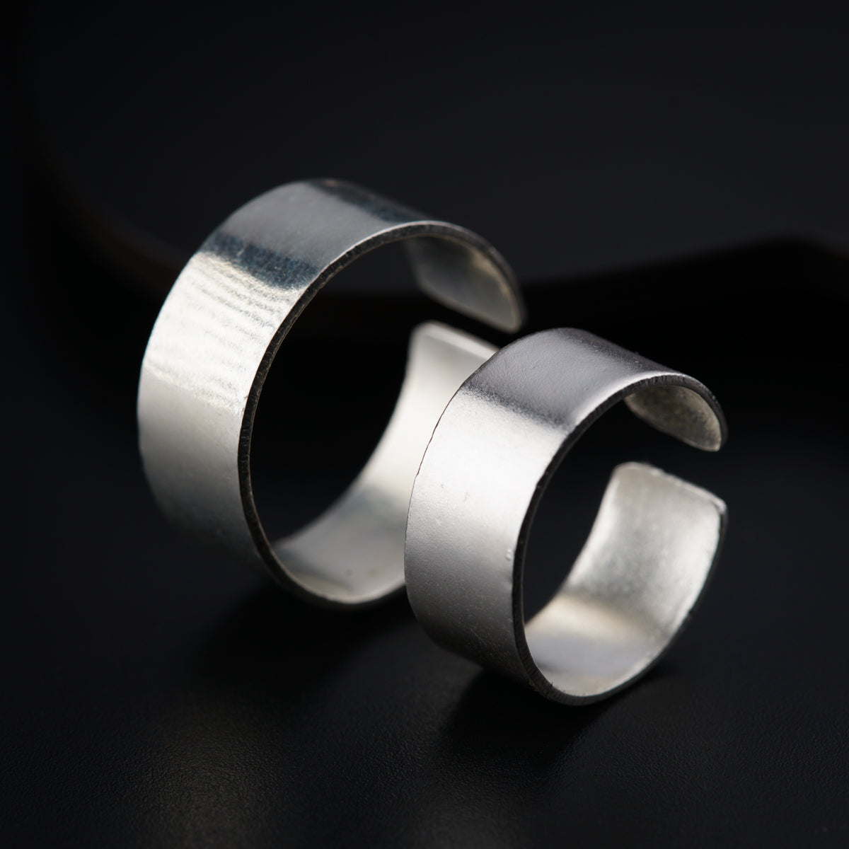 two silver rings sitting on top of a black surface