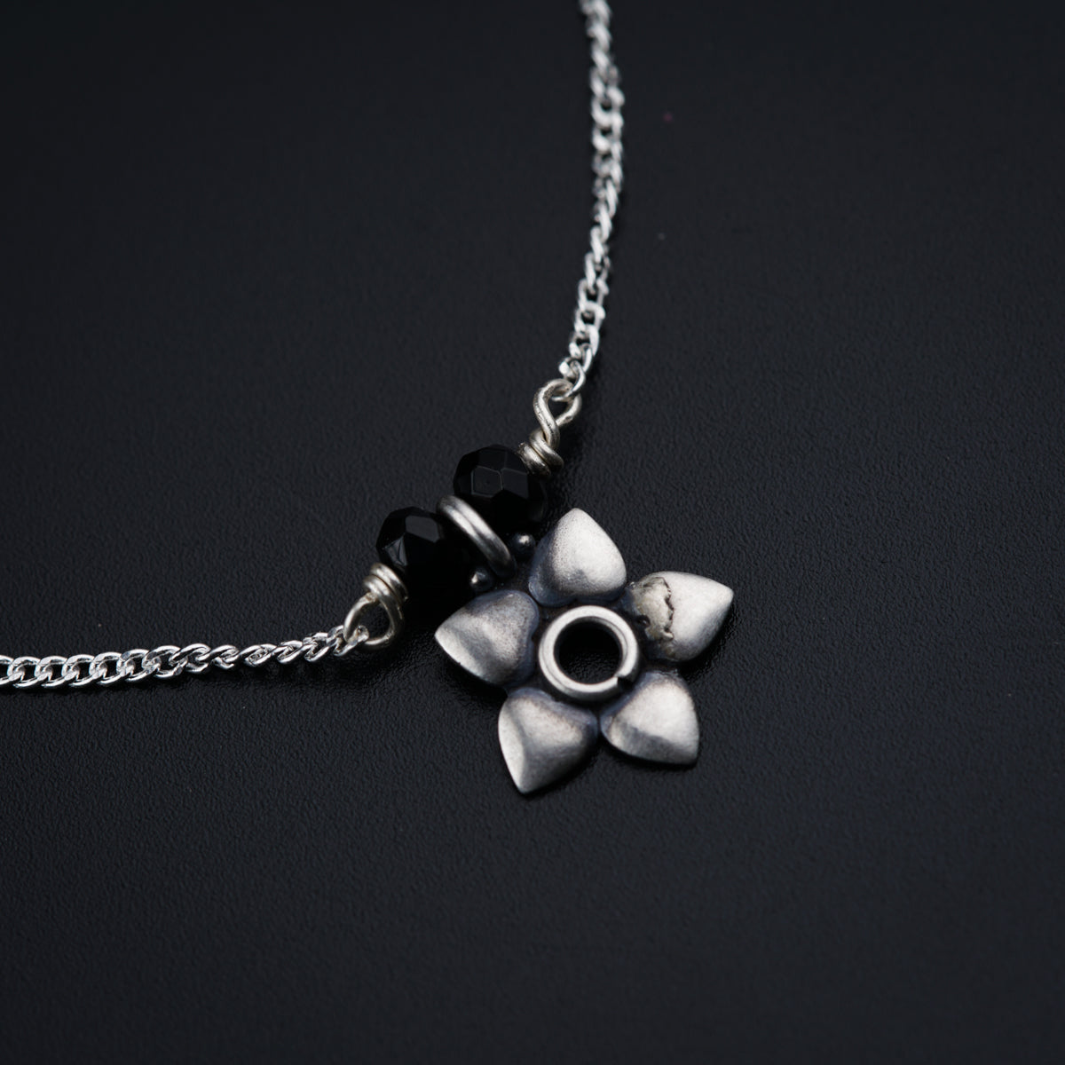 a silver necklace with a flower on it