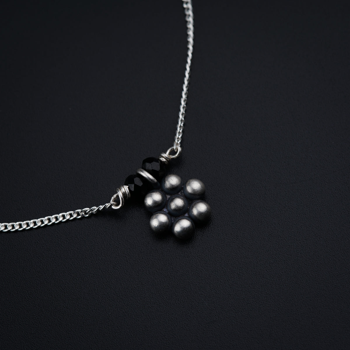 a black and white photo of a necklace on a black surface