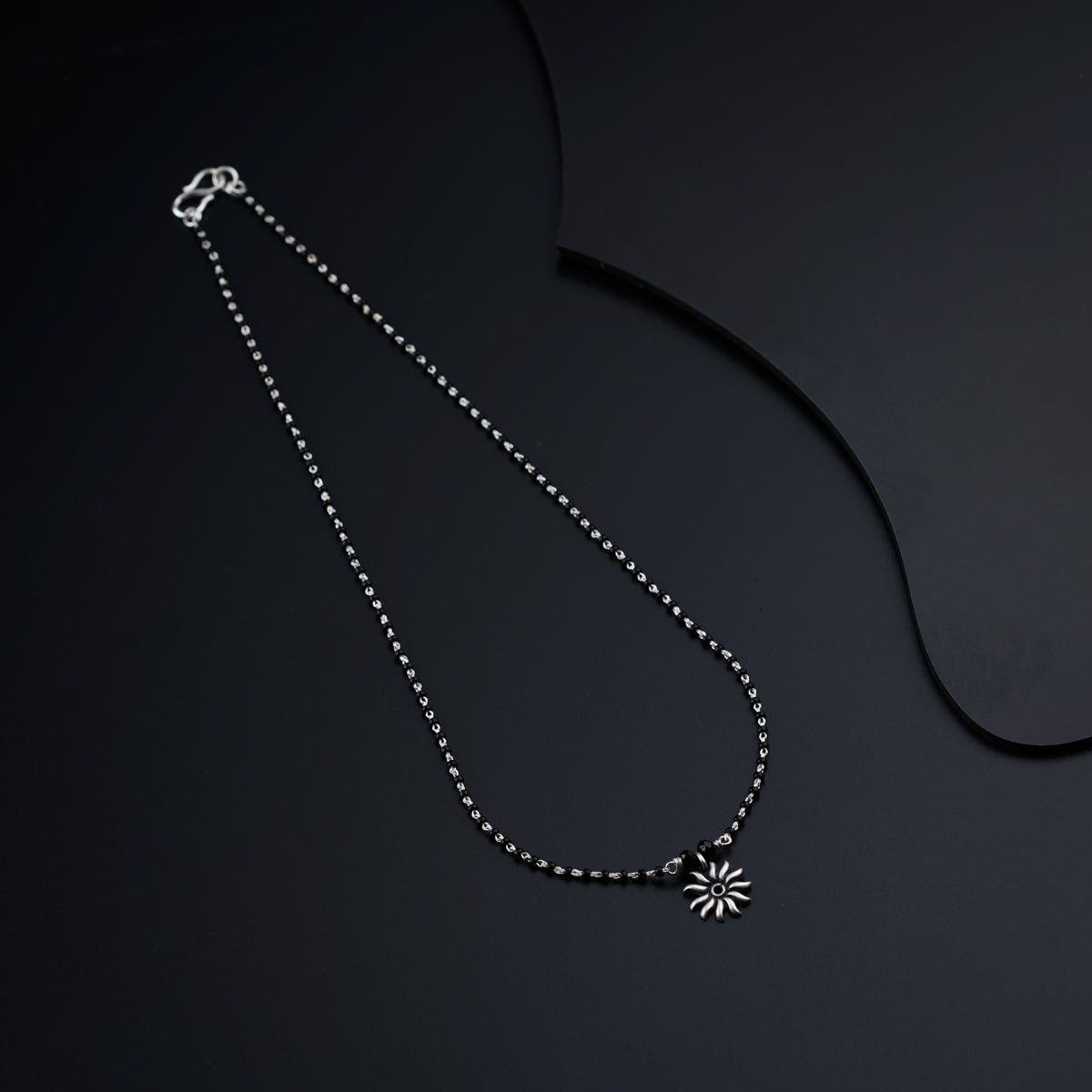 a black and white photo of a necklace on a black background