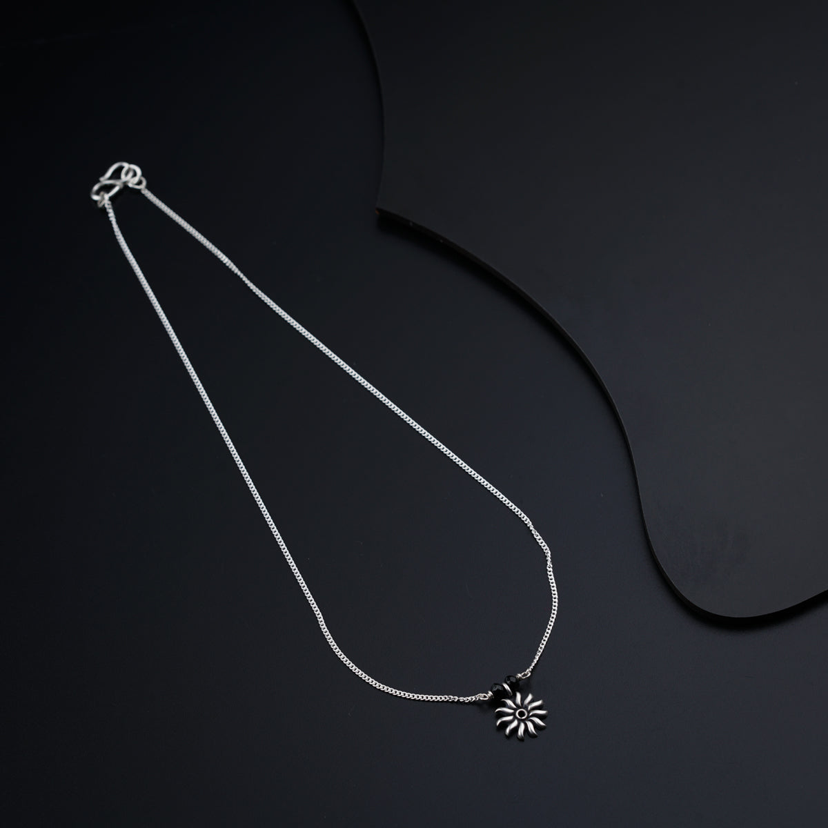 a necklace with a flower on a black background
