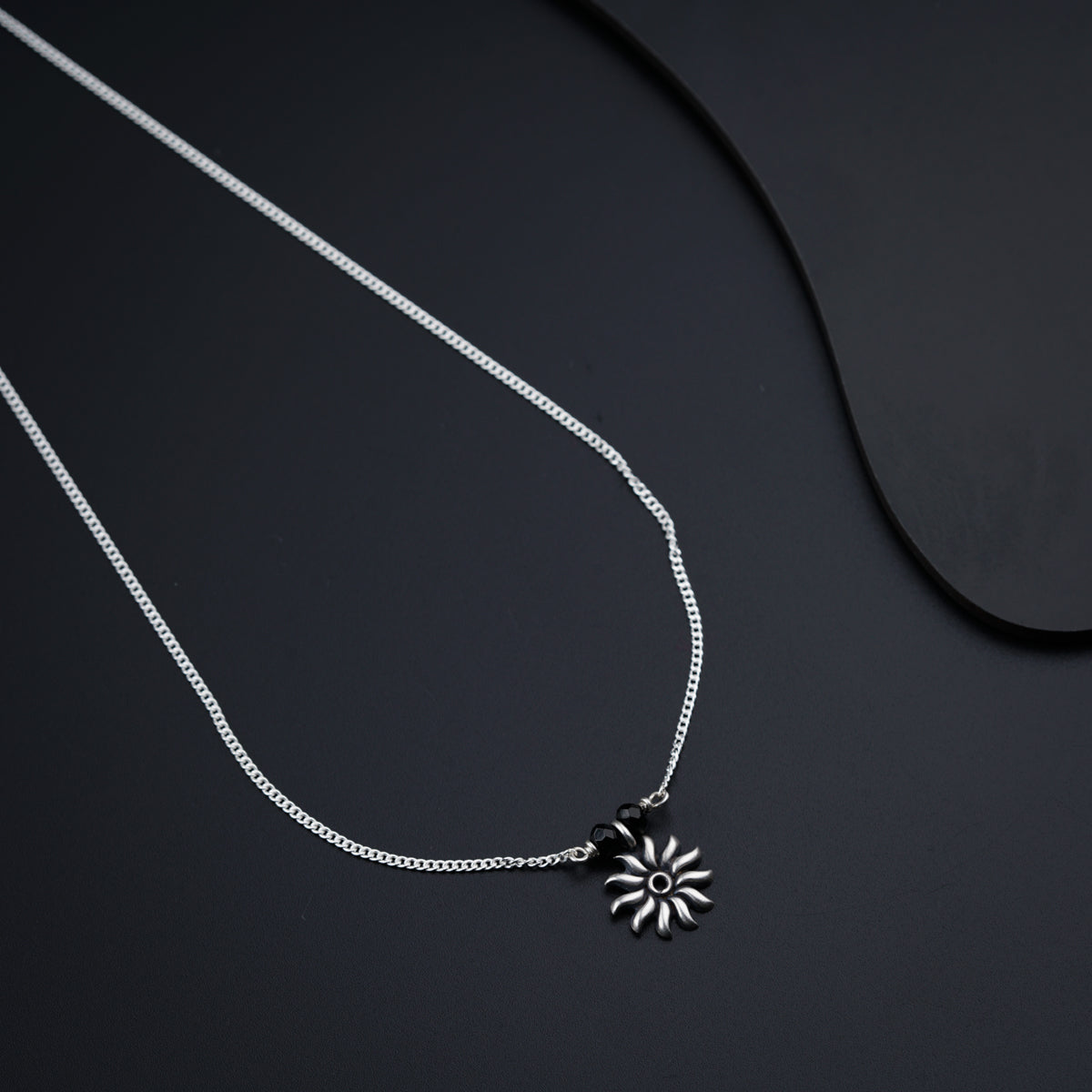 a black and white photo of a necklace on a black surface