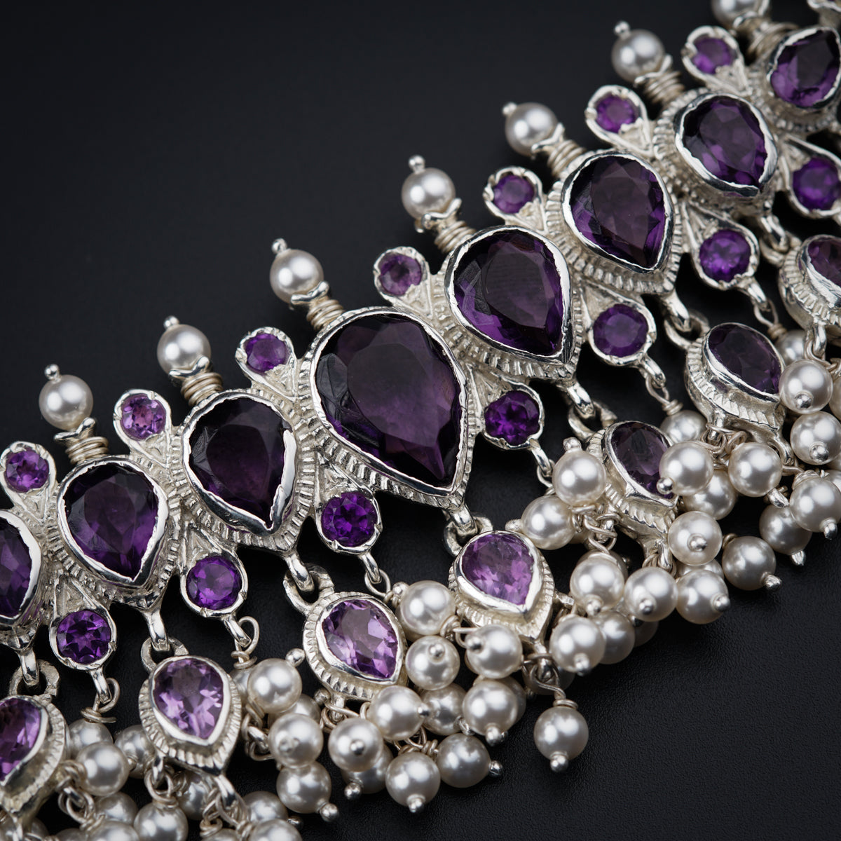 a close up of a bracelet with pearls and amethyst