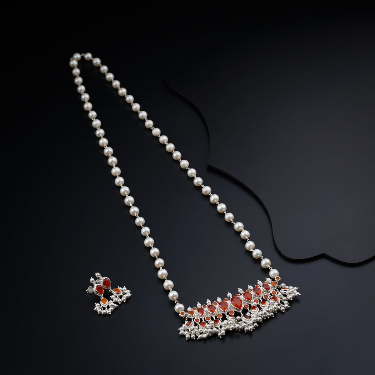 a necklace and earring with pearls on a black surface