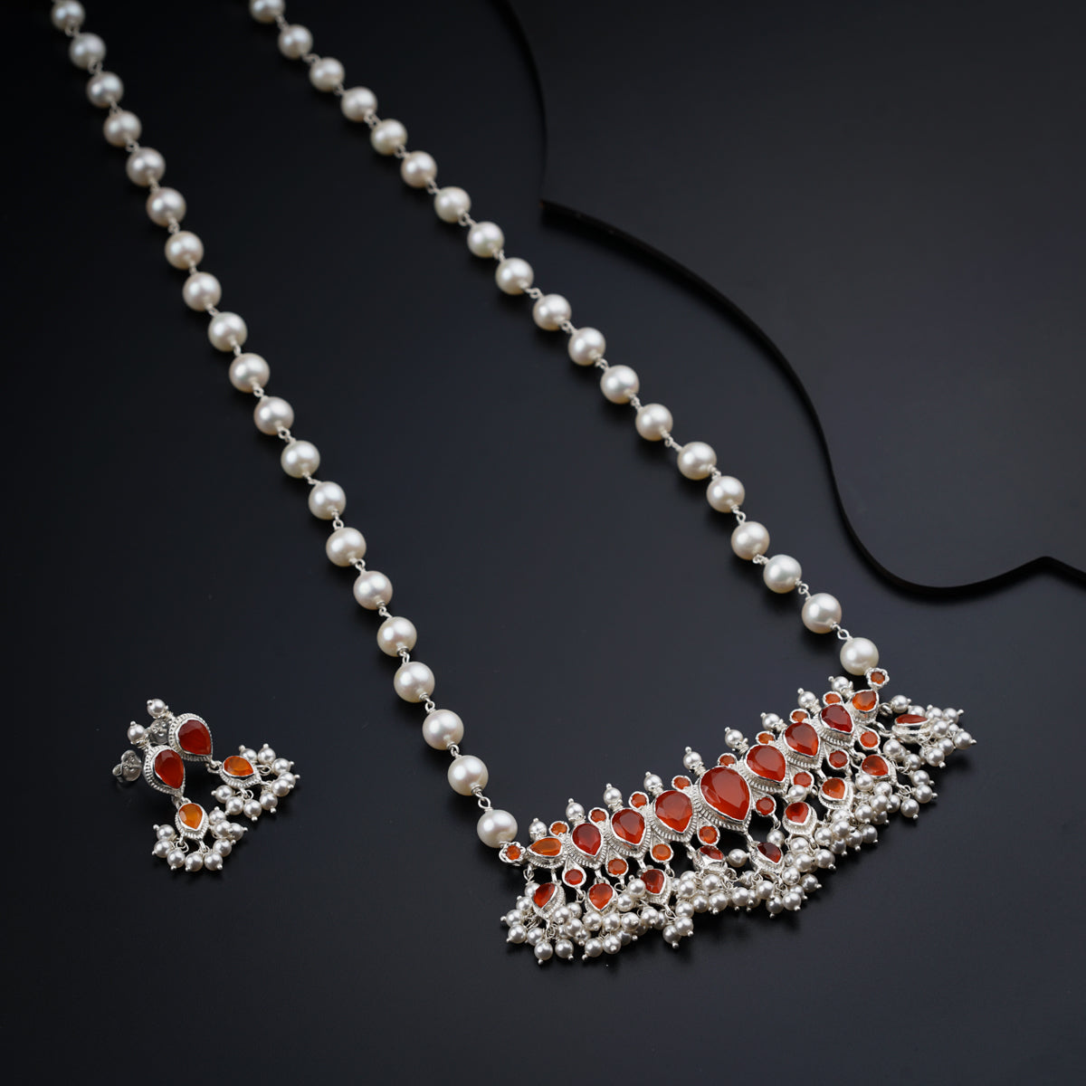 a necklace and earrings on a black surface