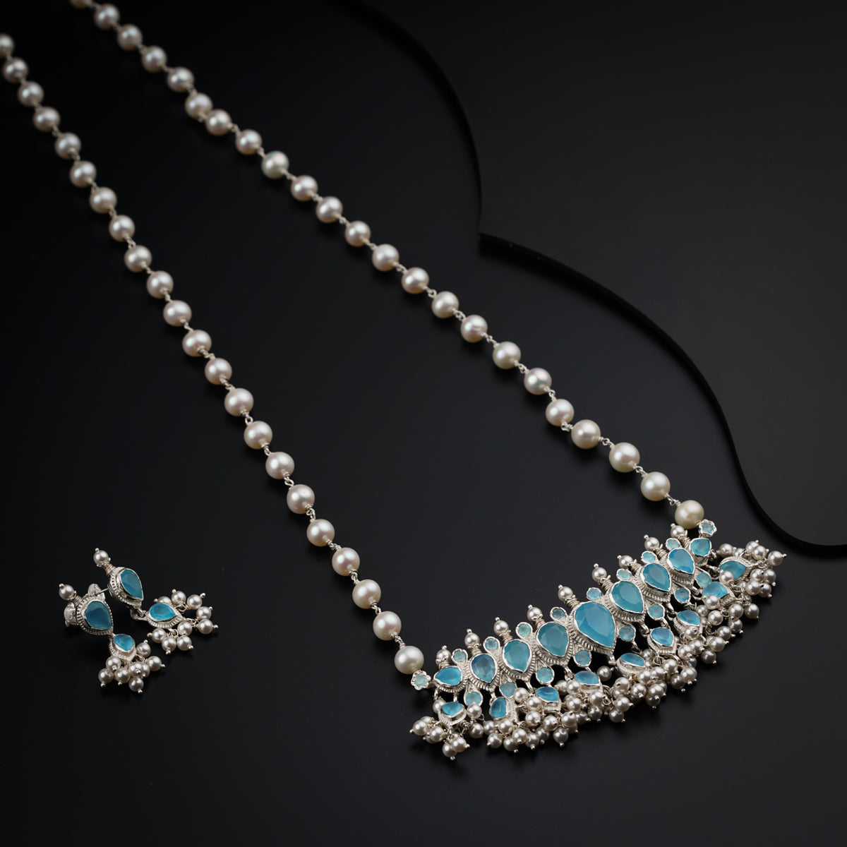 a close up of a necklace and earrings on a black surface