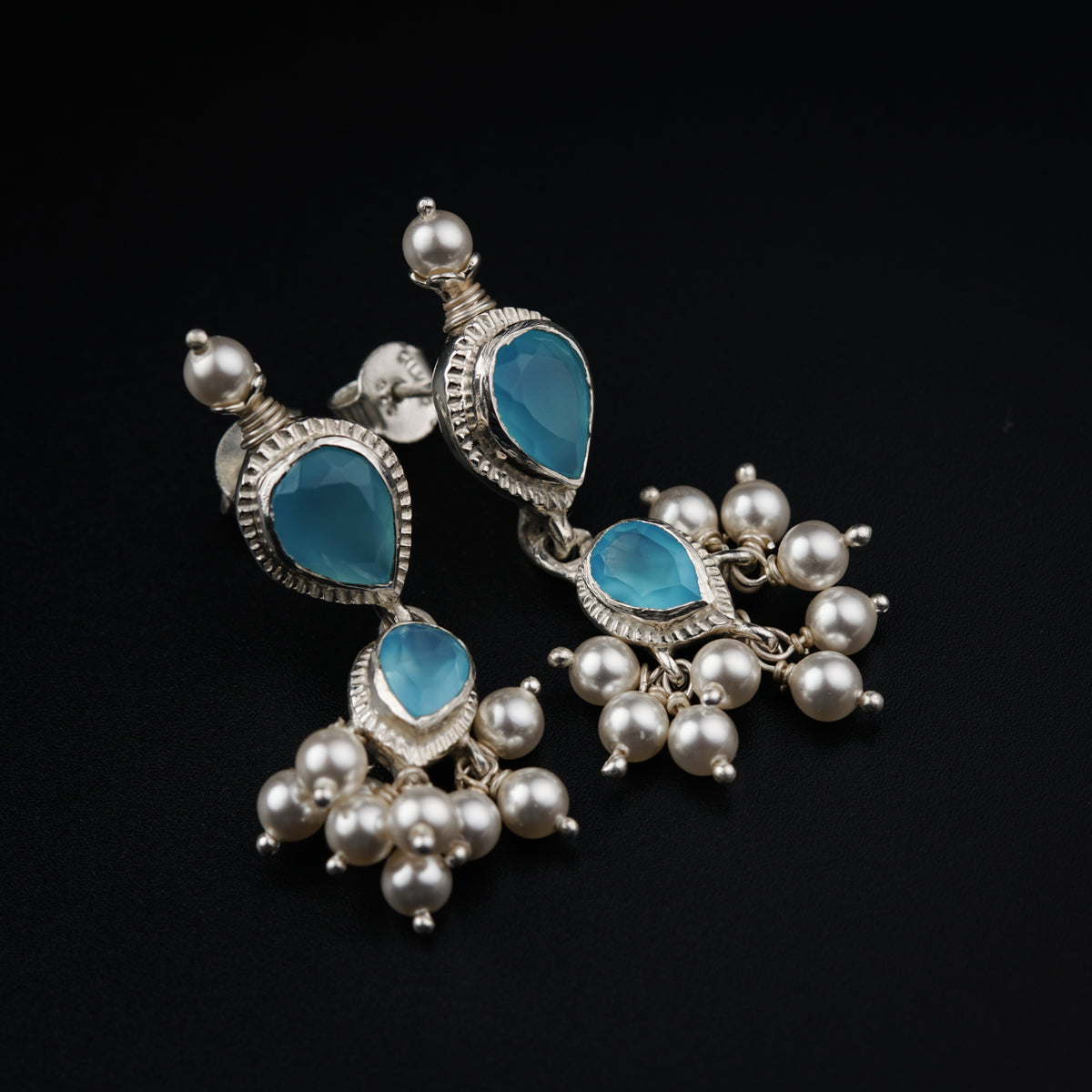 a pair of blue and white earrings on a black surface