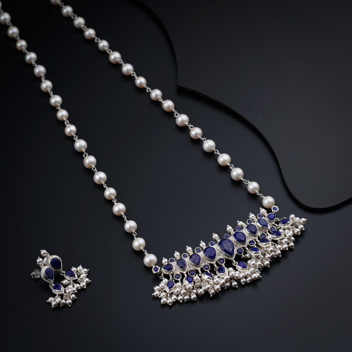 a close up of a necklace and earrings on a black surface