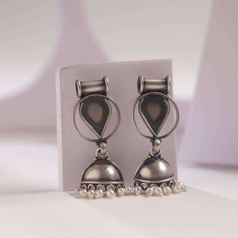 a pair of silver toned earrings with pearls
