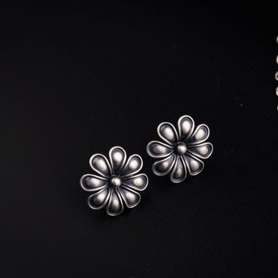 a pair of silver flower earrings on a black background