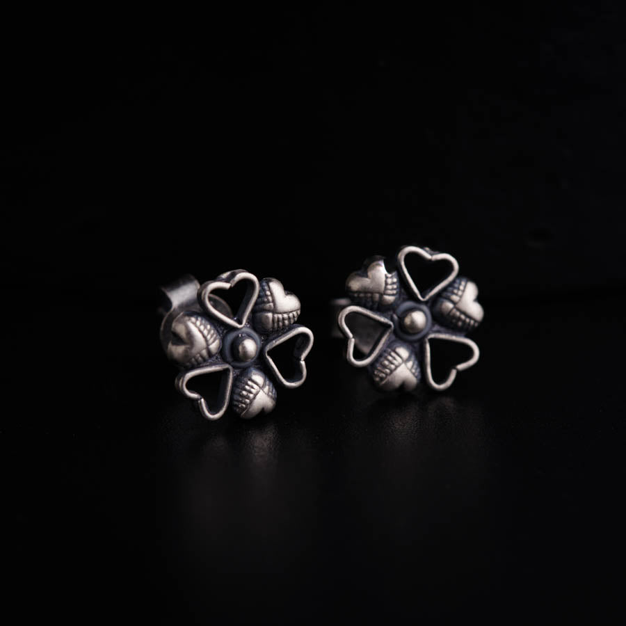 a pair of silver earrings on a black surface