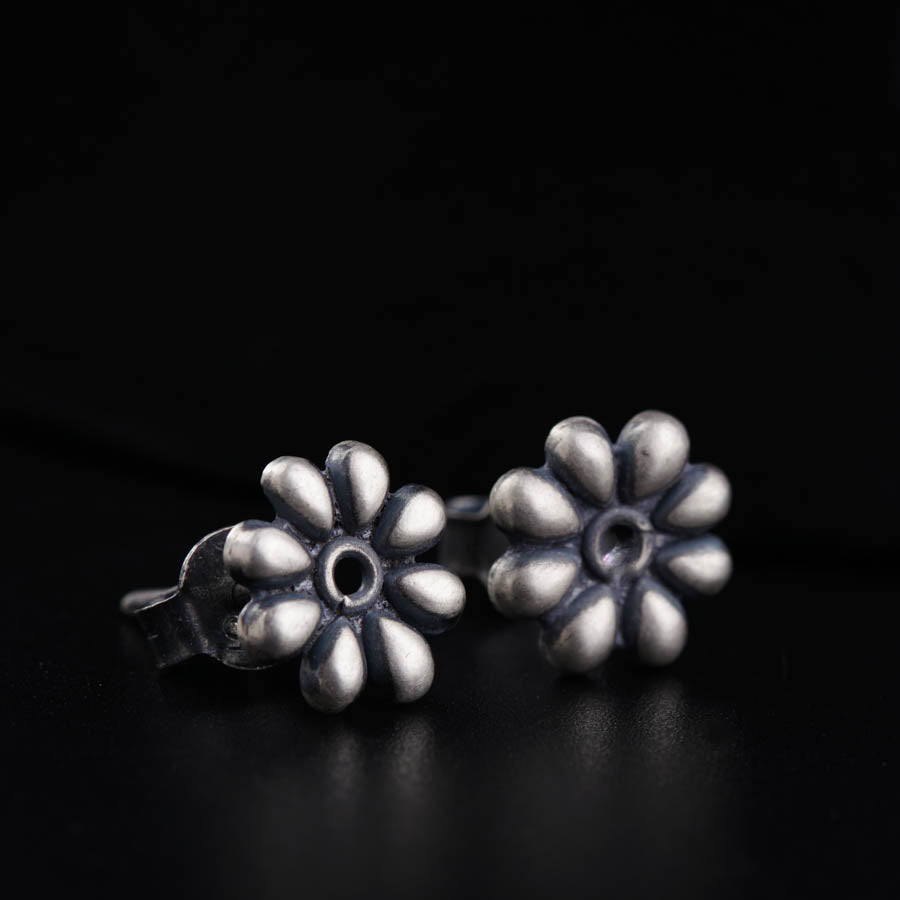 a pair of silver earrings on a black surface
