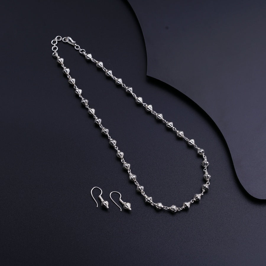 a necklace and earring on a black surface