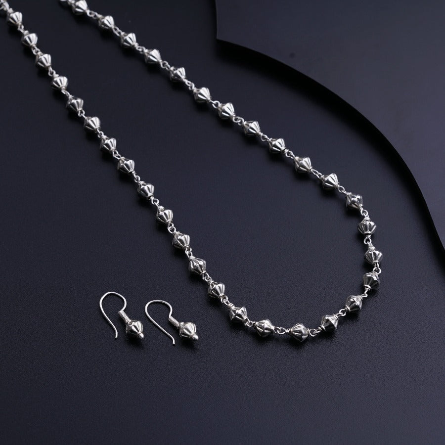 a necklace and earring set on a black surface