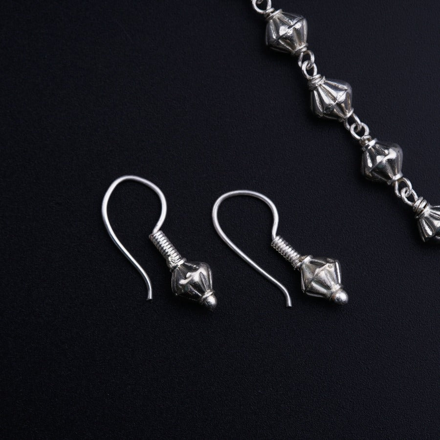a pair of silver earrings on a black surface