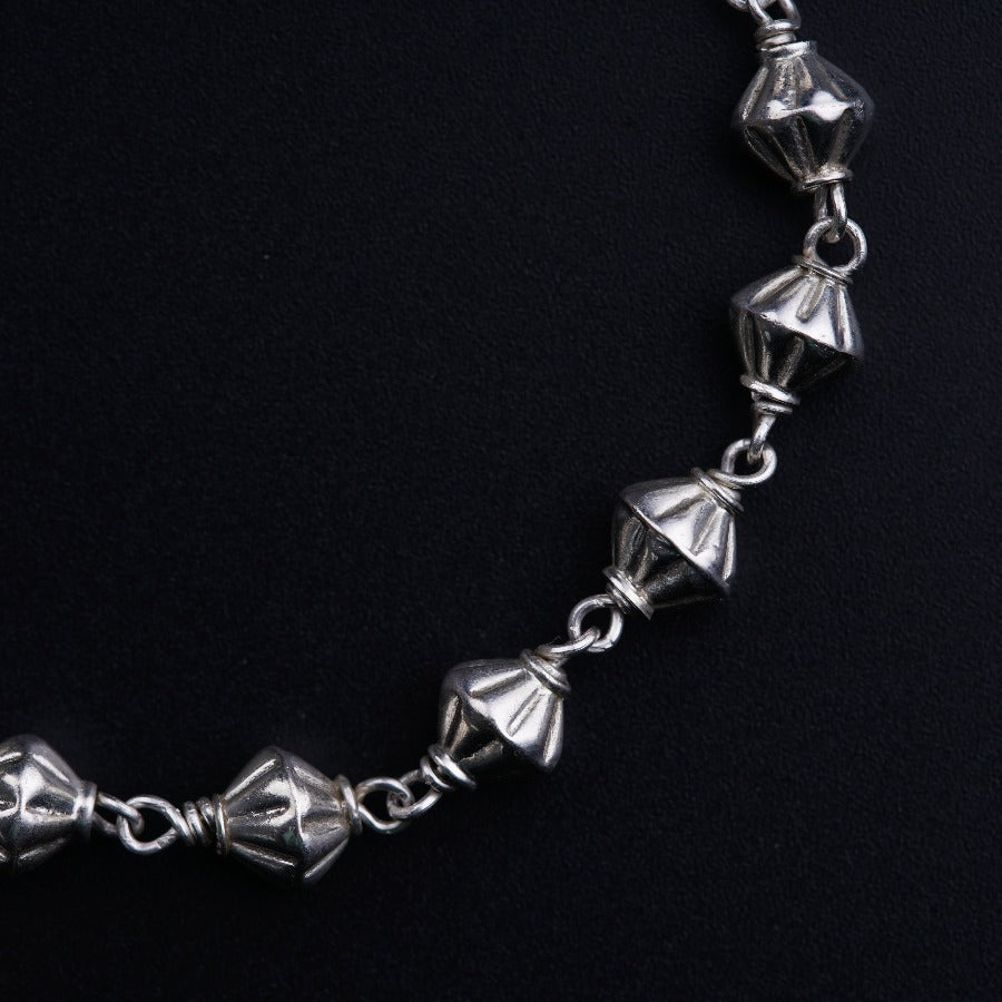 a close up of a silver bracelet on a black background