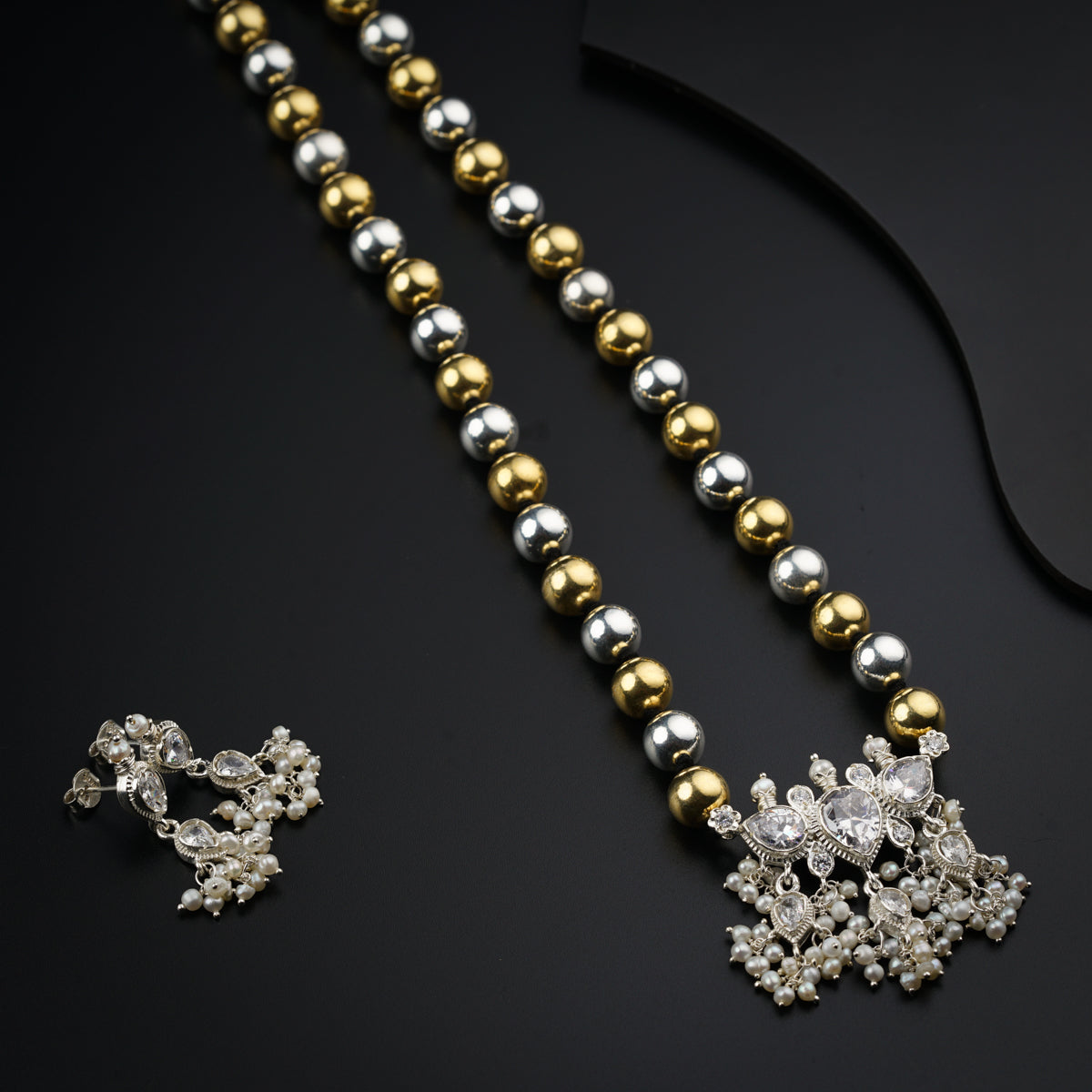 a gold and silver necklace with a pair of earrings