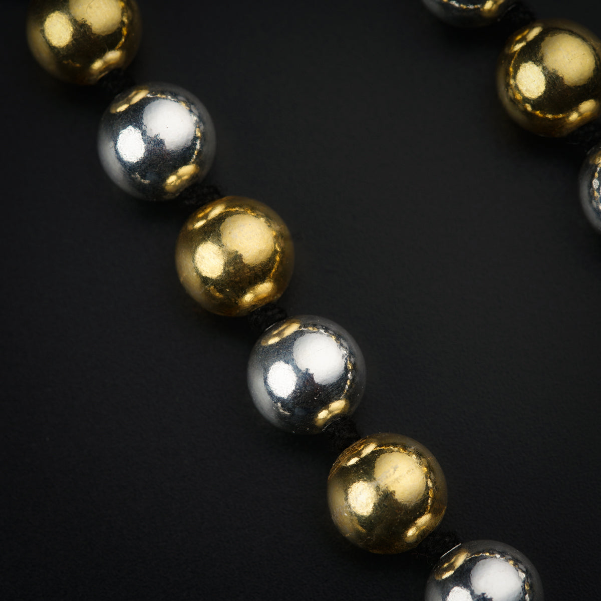 a gold and silver bead necklace on a black background