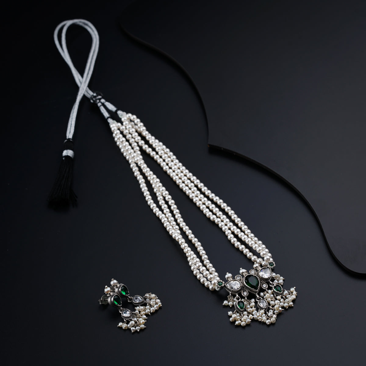 a pair of necklaces and earring on a black surface