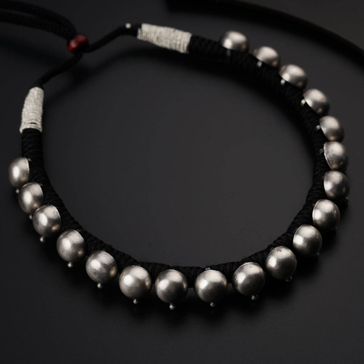 a black string bracelet with silver beads