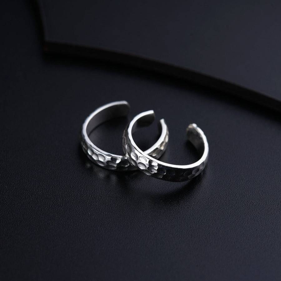 two silver rings sitting on top of a black surface