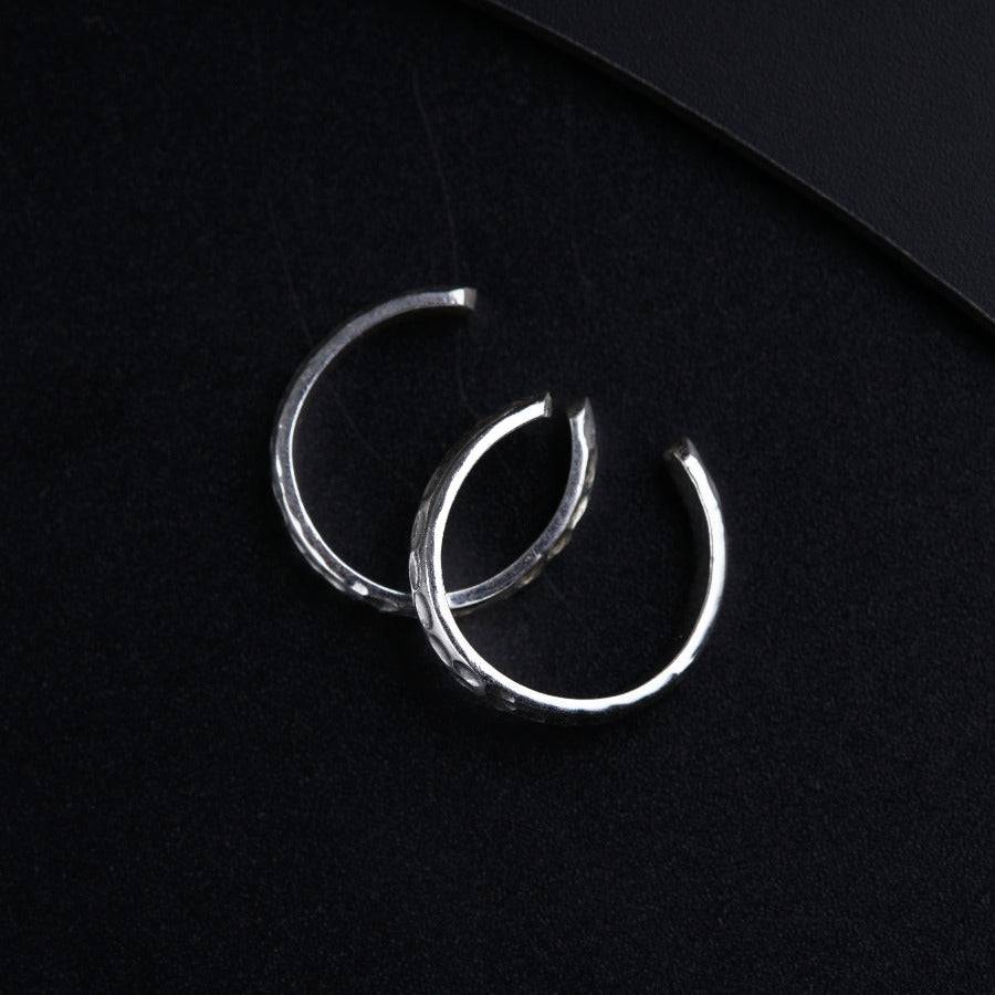 a pair of silver hoop earrings on a black surface