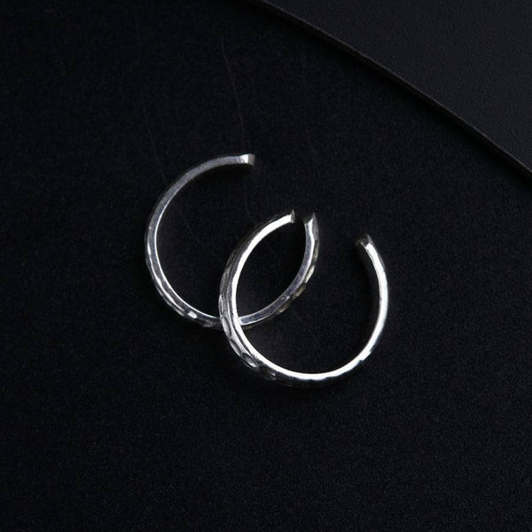 a pair of silver hoop earrings on a black surface