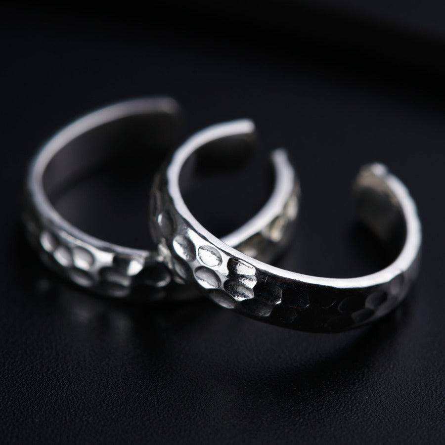 two silver rings sitting on top of a black surface