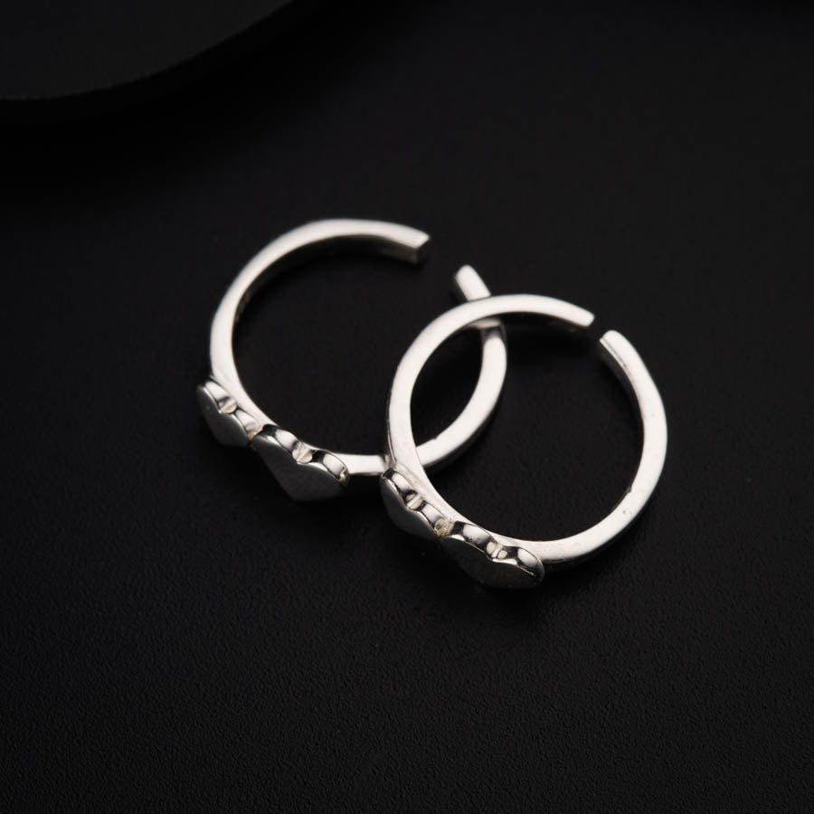 a pair of silver hoop earrings on a black surface