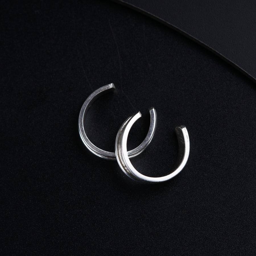 a pair of silver hoop earrings on a black surface