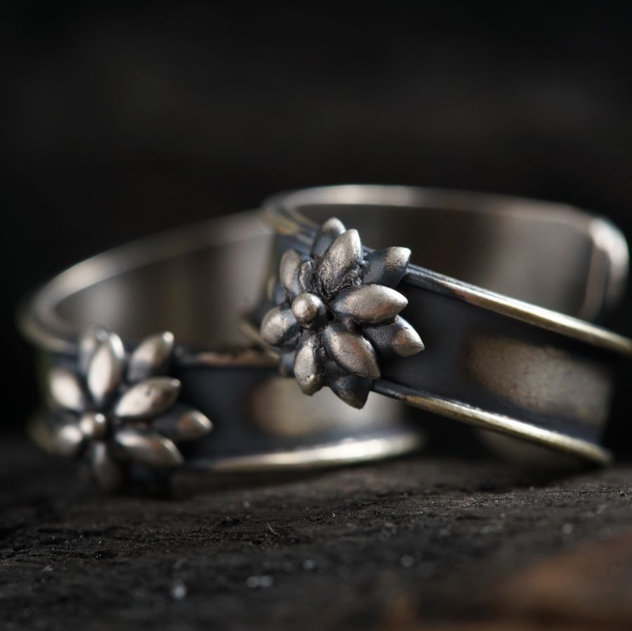 two silver rings with flowers on them sitting on a table