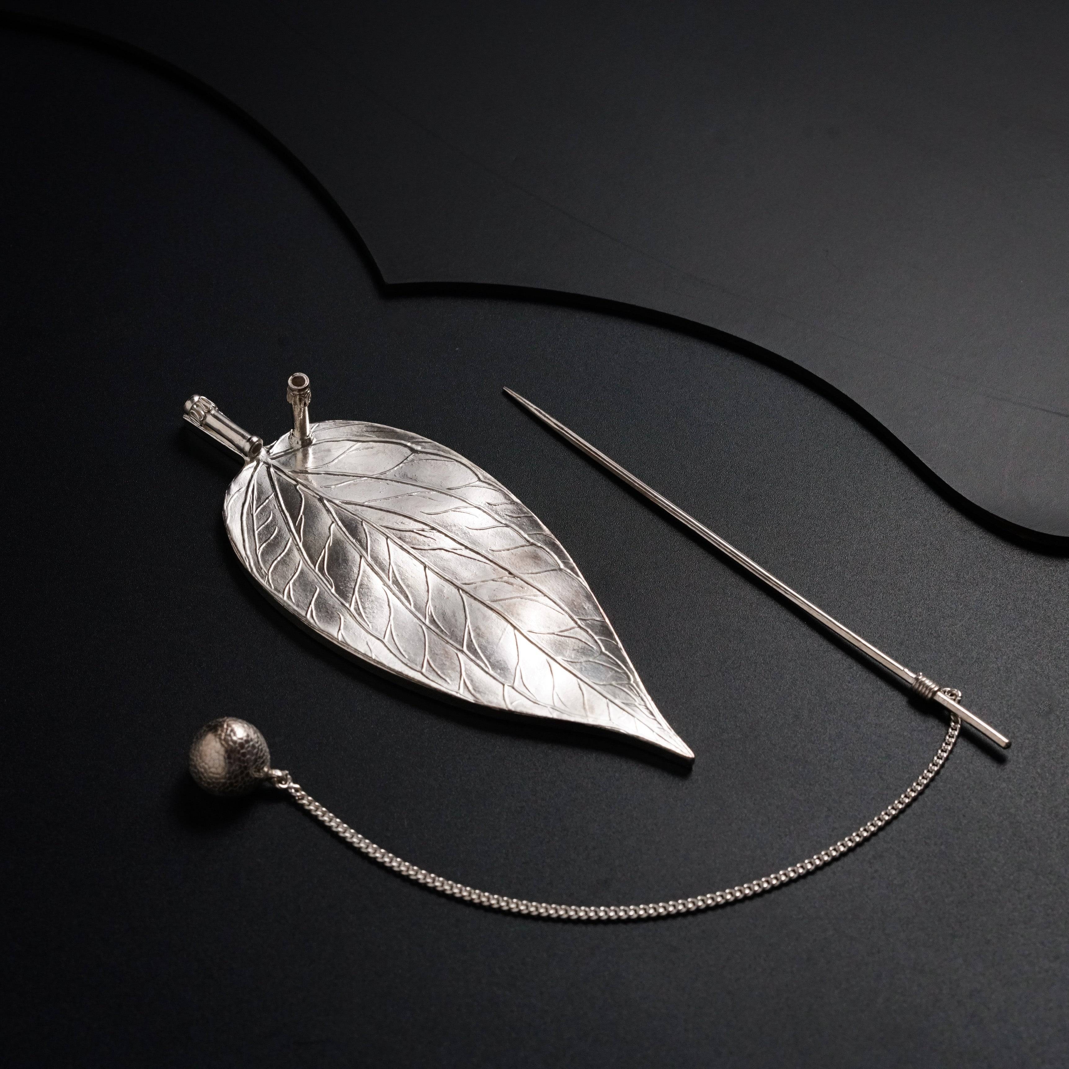 a silver necklace with a leaf on it