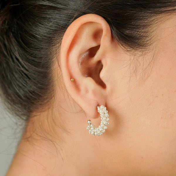 Close-up of pearl hoop earrings worn on ear, silver and pearl jewelry