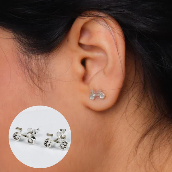 Close-up of silver bicycle-shaped earrings worn on ear
