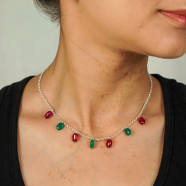 Close-up of silver necklace with red and green gemstone beads