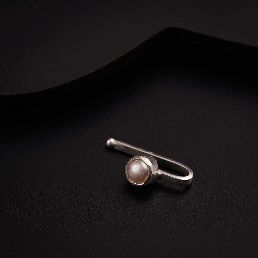 a ring with a pearl sits on a black surface