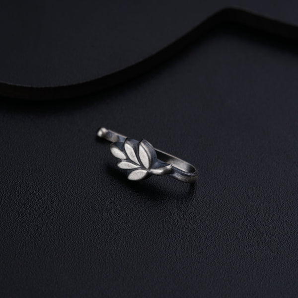 a silver ring with leaves on it sitting on a black surface